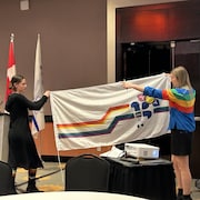 Deux personnes tiennent le drapeau de la francophonie inclusif de la Colombie-Britannique. 