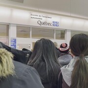 Des gens vus de dos dans une file d'attente.