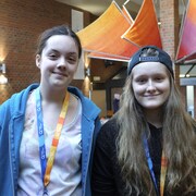 Deux jeunes filles sourient à la caméra, elles sont à l'intérieur de l'Université du Québec à Rimouski. 