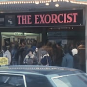 La façade d'un cinéma affichant le film « The Exorcist » et une foule massée à l'entrée. 