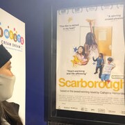 Une femme regarde l'affiche du film « Scarborough » avant d'entrer dans la salle de cinéma.