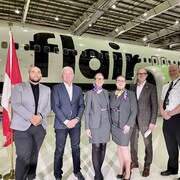 Courtney Walcott, Stephen Jones, Bob Sartor et Captain Matt Kunz debout devant un avion de la flotte de Flair Airlines dans un hangar.