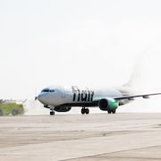 Un avion de la compagnie aérienne Flair roule sur la piste de l'aéroport de Charlottetown. Il est aspergé d'eau pour fêter son arrivée.