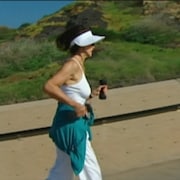 Femme qui fait de la course à pied en tenant de petits altères dans les mains. 