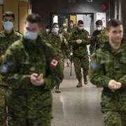 Des militaires des Forces armées canadiennes, la plupart portant un masque.  