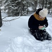 Deux adolescentes sont assises dans la neige et écrivent sur une feuille de papier. 
