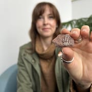 Anne MacFadyen montre le fossile, une patte de reptile incrustée dans une pierre.