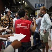 Un employé de la SNCF, vu de dos, donne des indications à des voyageurs à la station Montparnasse, à Paris.