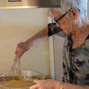 Une femme âgée prépare du sucre à la crème.
