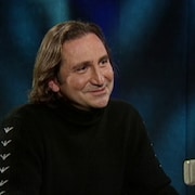 Franco Nuovo souriant derrière un micro. 