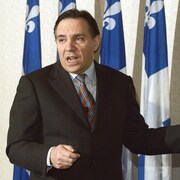 M. Legault devant une série de drapeaux québécois.
