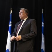 François Legault se tient debout devant des drapeaux du Québec.