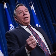 Le premier ministre du Québec François Legault parle au micro devant des drapeaux du Québec.