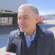 Le ministre François-Philippe Champagne en entrevue au micro de Radio-Canada, à l'extérieur, devant une usine,  