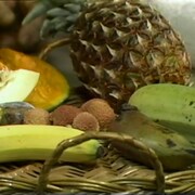 Panier avec des fruits exotiques comme un ananas, des litchis, une goyave et des bananes.