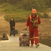 Un homme accompagné de ses enfants transportent des bagages avant d'évacuer. 
