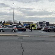 Des policiers dans un stationnement près d'un cordon de sécurité.