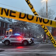 Un véhicule de police stationné à un carrefour, près du ruban de scène de crime à l'Université Brown, dimanche 14 décembre 2025, à Providence, dans le Rhode Island, après une fusillade survenue samedi 13 décembre 2025 à l'Université. 