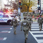 Des militaires de la Garde nationale traversent la rue pr&egrave;s d'un amas de v&eacute;hicules de police, &agrave; Washington, le 26 novembre 2025.