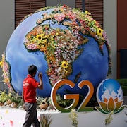 Le logo du G20 devant une planète Terre fleurie. 