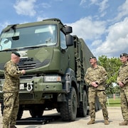 Des militaires en uniforme devant un camion de l'armée.