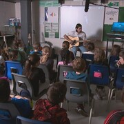 Des élèves écoutent un chanteur dans une classe.