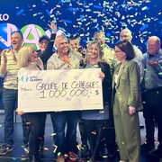 Un groupe d'employés sous les confettis, devant une pancarte affichant la somme remportée d'un million de dollars.