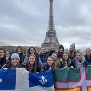 L'équipe porte deux drapeaux du Québec et de la région. On voit la tour Eiffel à l'arrière.