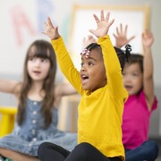 Des enfants lèvent les bras en chantant.