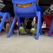 Les pieds d'enfants assis sur des chaises dans une garderie.