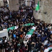 Des corps portés par une foule dans une mosquée