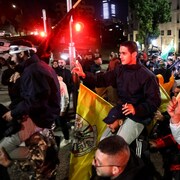 Des jeunes hommes portés sur les épaules de manifestants brandissant des drapeaux.