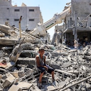 Un garçon assis sur des ruines d'une mosquée détruite par une frappe aérienne.