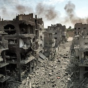 Vue aérienne de dizaines de bâtiments presque entièrement démolis, tandis que leurs débris recouvrent la rue.