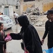 Une femme distribue un sac de nourriture à une fillette, à Rafah, dans la bande de Gaza, en avril 2024.