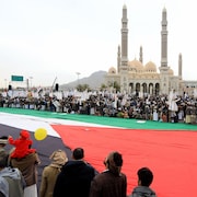 Des manifestants yéménites rassemblés autour d'un drapeau palestinien géant à Sanaa, capitale du Yémen.
