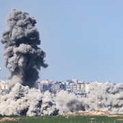 Une épaisse fumée noire se dégage des décombres d'un bâtiment bombardé par l'armée israélienne à Gaza.