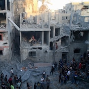 Des secouristes et des civils fouillent les décombres d'immeubles bombardés.