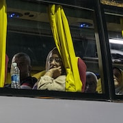 Une femme regarde par la fenêtre d'un bus.