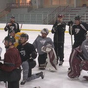 Des joueurs de hockey à genoux sur la une patinoire lors d'un entraînement. 