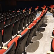 Une salle de spectacles vide, plusieurs chaises. 