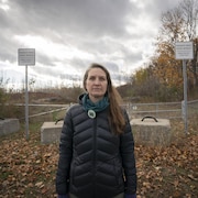 Geneviève Lussier se tient à l'extérieur de la forêt, dont l'accès est interdit au public. Une clôture et des pancartes indiquant «Propriété privée» se trouvent aux abords du terrain.
