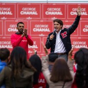 George Chahal applaudit alors que Justin Trudeau lève un bras au ciel devant une foule qui les acclame.