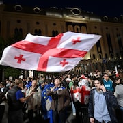 Des centaines de manifestants sont rassemblés, certaines personnes brandissant le drapeau géorgien, d'autres, le drapeau européen.