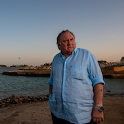 Gérard Depardieu debout sur une plage.