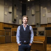 Un homme pose dans un studio d'enregistrement de musique. 