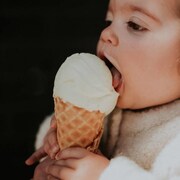 Un jeune enfant mange une glace à la vanille dans un cornet