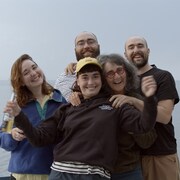 Une famille de cinq personnes devant un plan d'eau sourit à la caméra.