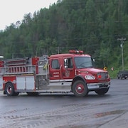 Un camion de pompiers et une pelle mécanique barrent une route.