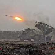 Un lance-missile russe tire sur les positions ukrainiennes dans un champ dévasté.